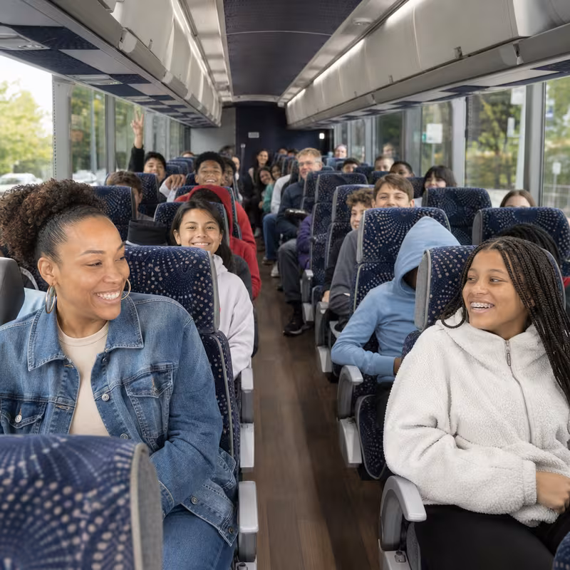Group boarding a white charter bus for School Transportation transportation in Princeton