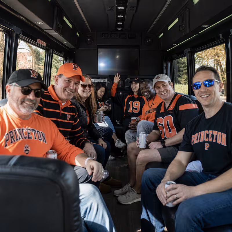 Group boarding a white charter bus for Sporting Event Transportation transportation in Princeton